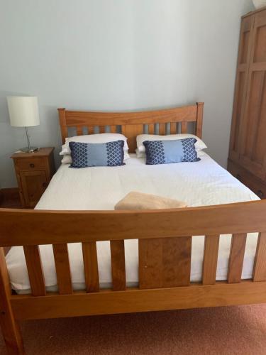 a bedroom with a wooden bed with two blue pillows at One Panama in Martinborough 