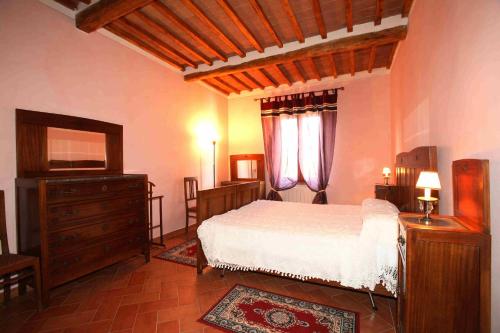 a bedroom with a bed and a dresser and window at Villa Il Colle di Monteaperti in Casetta