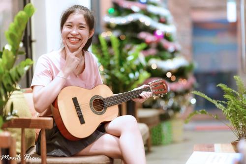 a woman sitting in a chair holding a guitar at Mojzo Inn Boutique Hotel in Nha Trang