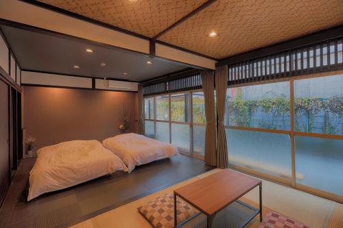 a bedroom with a bed and a table and windows at Yoshimura ooike sense in Fujikawaguchiko