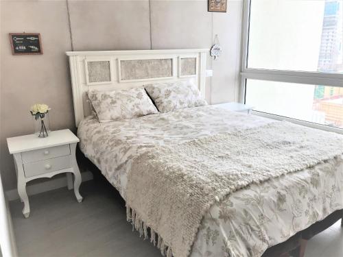 コンコンにあるConcón Costa de Montemar Departamento, 3 dormitoriosの白いベッドルーム(ベッド1台、ナイトスタンド、窓付)