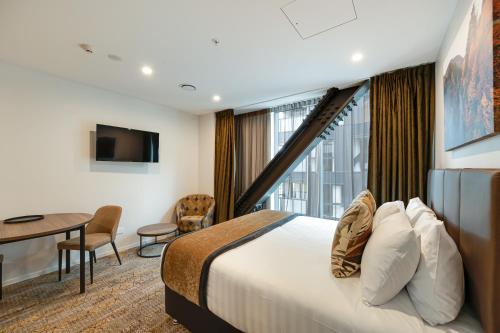 a hotel room with a bed and a desk and a window at La Quinta by Wyndham Remarkables Park Queenstown in Queenstown