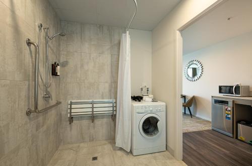 a bathroom with a washing machine and a shower at La Quinta by Wyndham Remarkables Park Queenstown in Queenstown