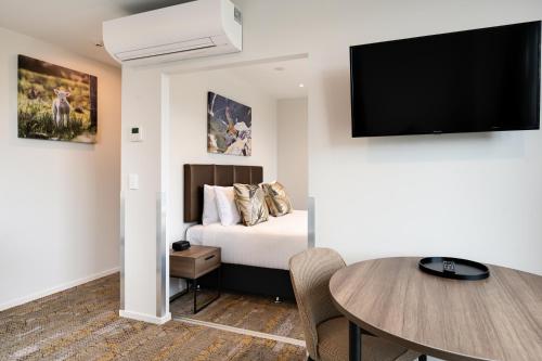 a bedroom with a bed and a table and a tv at La Quinta by Wyndham Remarkables Park Queenstown in Queenstown