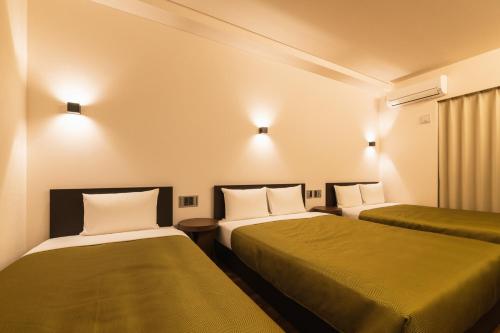 福岡市にあるHotel Iori ホテル庵のホテルルーム ベッド2台&緑のシーツ付