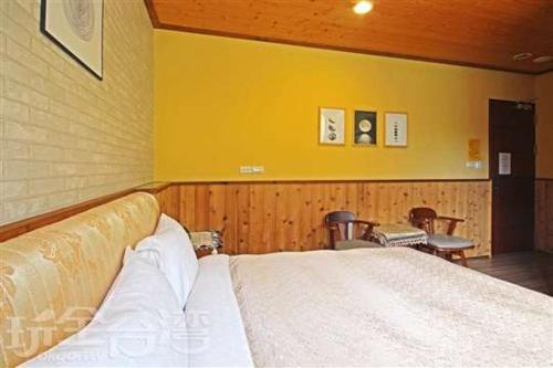 a bedroom with a bed and a yellow wall at Sun Moon Lake Tan Hsiang Yu B&B in Yuchi