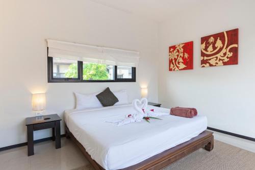 a bedroom with a white bed with a flower on it at Foxtail Palm Villa in Rawai Beach