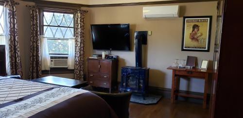 a bedroom with a bed and a flat screen tv at Cabernet House, an Old World Inn in Napa