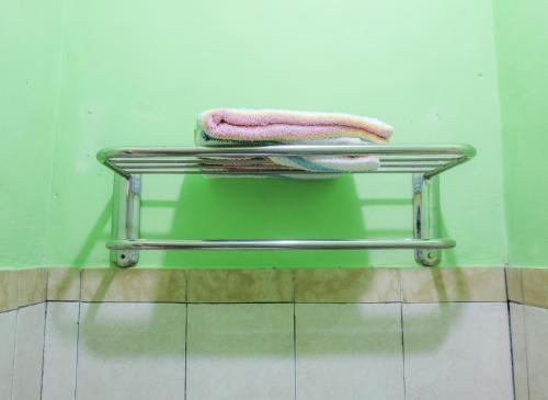 a towel rack in a bathroom with a green wall at Umah Hijau Tabanan in Tabanan