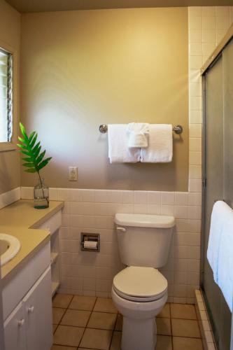 a bathroom with a toilet and a sink and towels at Napili Village Hotel in Kahana