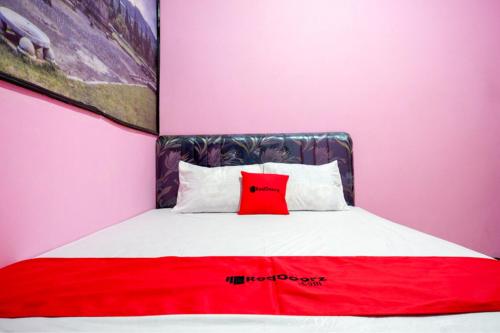 a bedroom with a red pillow on a bed at RedDoorz Syariah near Telaga Warna Dieng in Dieng