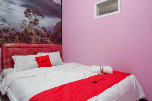 a bedroom with pink walls and a bed with red pillows at RedDoorz Syariah near Telaga Warna Dieng in Dieng