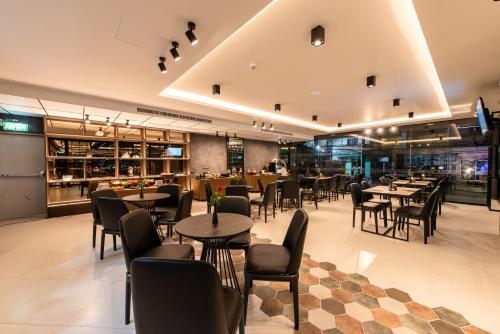 a restaurant with tables and chairs and a bar at Blackwoods Hotel Pattaya - SHA Extra Plus in Pattaya