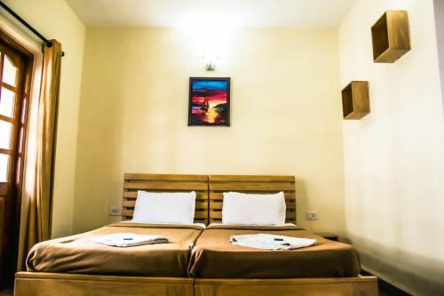 una camera con un letto con due cuscini sopra di Utopia Holiday Candolim a Candolim