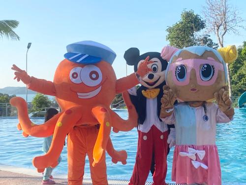 three people dressed up in costumes standing next to a pool at MyRus Resort Langkawi in Pantai Cenang