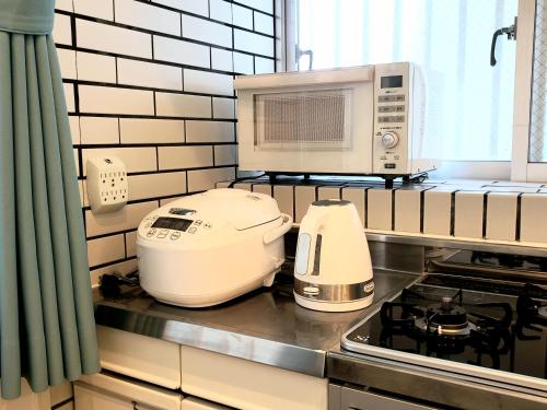 a kitchen with a toaster and a microwave on the counter at "沖縄の美ら海をイメージしたコンセプトルーム&スマートハウス, 人気のリゾートタウン北谷で暮らすように過ごす, ゆったり64平米2LDK" Villa Blu Okinawa Chatan 2-1 ヴィラブルー沖縄北谷2-1 in Chatan