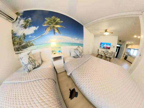 2 camas en una habitación con un mural de palmeras en Villa Blu Okinawa Chatan 2-1 ヴィラブルー沖縄北谷2-1 "沖縄アリーナ徒歩圏内の民泊ホテル", en Chatan