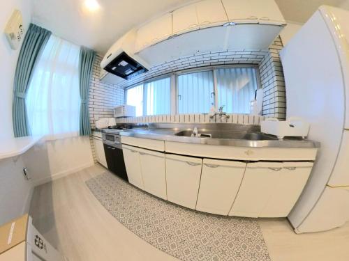 a kitchen with a sink and a large window at "沖縄の美ら海をイメージしたコンセプトルーム&スマートハウス, 人気のリゾートタウン北谷で暮らすように過ごす, ゆったり64平米2LDK" Villa Blu Okinawa Chatan 2-1 ヴィラブルー沖縄北谷2-1 in Chatan