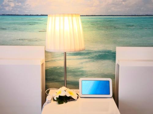a table with a lamp and a laptop on it at "沖縄の美ら海をイメージしたコンセプトルーム&スマートハウス, 人気のリゾートタウン北谷で暮らすように過ごす, ゆったり64平米2LDK" Villa Blu Okinawa Chatan 2-1 ヴィラブルー沖縄北谷2-1 in Chatan