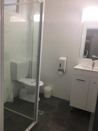 a bathroom with a toilet and a glass shower at Peppercorn motor inn in Narromine