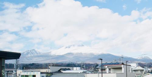 a snow covered mountain in front of a city at Compass Karuizawa in Karuizawa