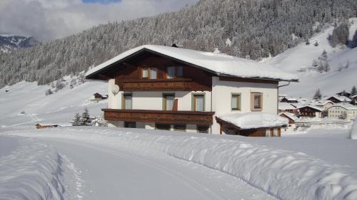 a house covered in snow in front of a mountain at Haus Annemarie Apartments Kartitsch - Hochpustertal in Kartitsch