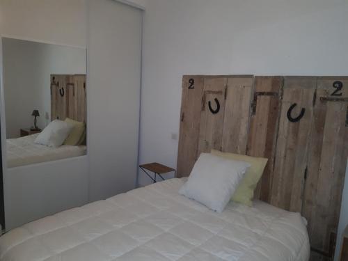 une chambre avec un lit blanc avec une tête de lit en bois dans l'établissement SETE VUE EXCEPTIONNELLE, à Sète
