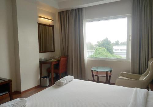 a hotel room with a bed and a window at Grand Gardenia in Tiruchchirāppalli