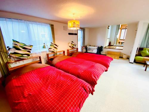 two beds in a room with red sheets at Ecco's House エッコズハウス in Shiraoi