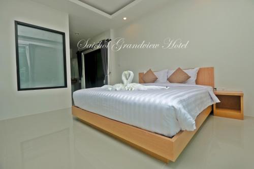 a bedroom with a large bed with a white comforter at Saichon Grand View in Ban Lam Rua Taek