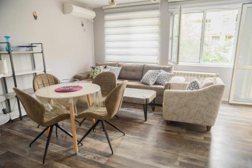 uma sala de estar com um sofá, uma mesa e cadeiras em Apartment MARTINI em Burgas