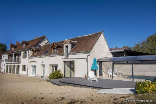 une grande maison blanche avec une terrasse et un bâtiment dans l'établissement Gite Domaine de Trevety, à Châtillon-sur-Cher
