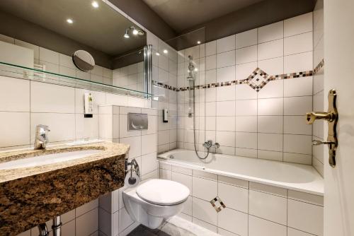 a bathroom with a toilet and a sink and a tub at Hotel Wassersleben in Flensburg