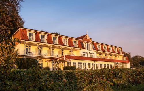 a large yellow building with a red roof at Hotel Wassersleben in Flensburg