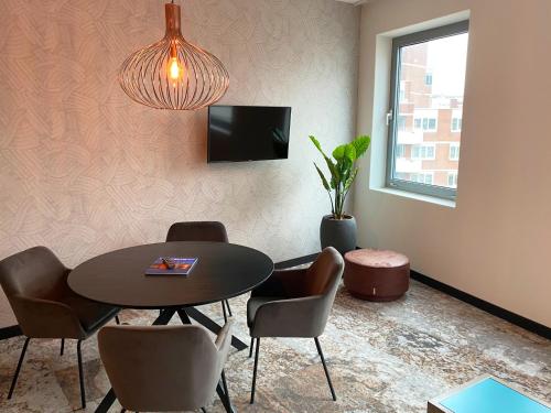 a dining room with a table and chairs and a tv at Fletcher Hotel-Restaurant Scheveningen in Scheveningen