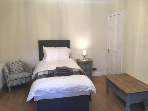 a bedroom with a bed and a chair and a table at Number One in Haddington