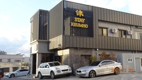 two cars parked in front of astay kerkvo building at Hotel HueStay-KeumHo in Seogwipo