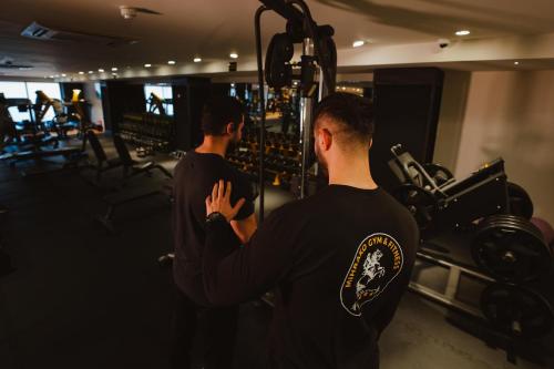 two men standing in a gym looking at a machine at Mihrako Hotel & Spa in As Sulaymānīyah