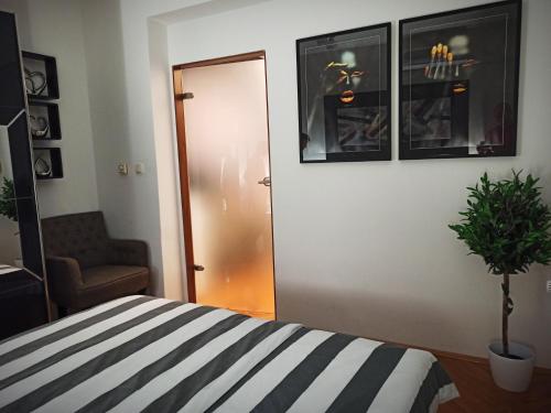a bedroom with a striped bed and a chair and a door at Apartman Aurelius - private parking in Osijek