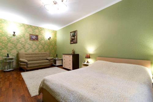 a green bedroom with a bed and a chair at Nadezhda Apartments on Gogolya 117 in Almaty