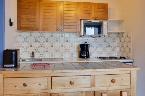 a kitchen with wooden cabinets and a counter top at Vacancéole - Résidence Quirlies in Les Deux Alpes