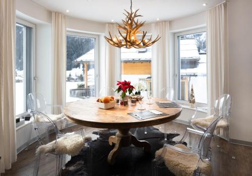 a dining room with a wooden table and a chandelier at Apartmenthaus Mountainvista in Kleinarl
