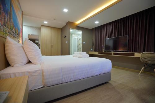 a hotel room with a bed and a flat screen tv at The Qube fifty Hotel in Bangkok