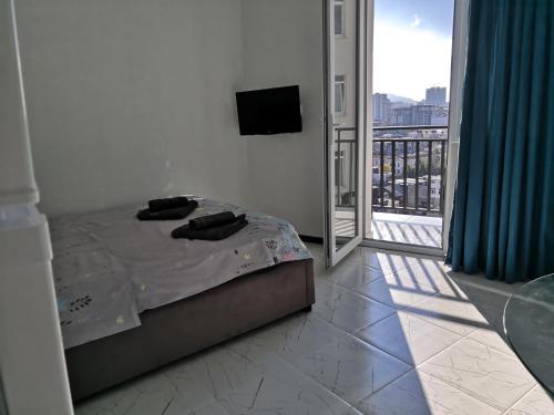 a bedroom with a bed and a balcony with a television at Lovely Apartment in City Center in Batumi