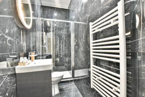 La salle de bains noire est pourvue d'un lavabo et de toilettes. dans l'établissement Welcoming apartment - 1BR-4P -Grands Boulevards, à Paris