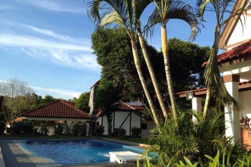a pool in front of a house with palm trees at Villa Mommy A Famosa Resort in Melaka