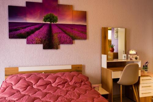 a bedroom with a pink bed and a desk and a painting at Апартамент Lavander Fleur in Nesebar
