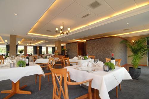 a dining room with white tables and wooden chairs at Hotel Inkelshoes in Epen