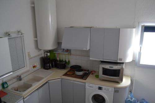 eine kleine Küche mit einer Spüle und einer Mikrowelle in der Unterkunft Maison 300 m de la plage in Châtelaillon-Plage