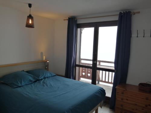Un dormitorio con una cama y una ventana grande. en Appt 43 m2 Station Auris en Oisans - Alpes d huez, en Auris